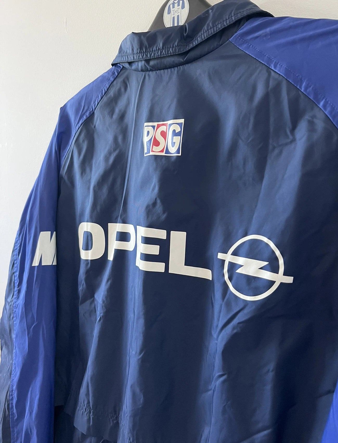 Veste bleue du PSG de la saison 1998/1999. On peut retrouver l'équipementier Nike et le sponsor Opel. Il s'agit d'une veste authentique d'époque.