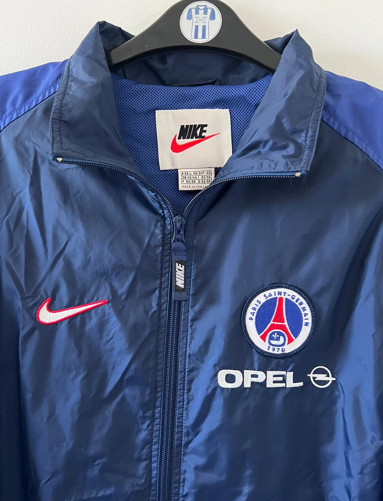 Veste bleue du PSG de la saison 1998/1999. On peut retrouver l'équipementier Nike et le sponsor Opel. Il s'agit d'une veste authentique d'époque.