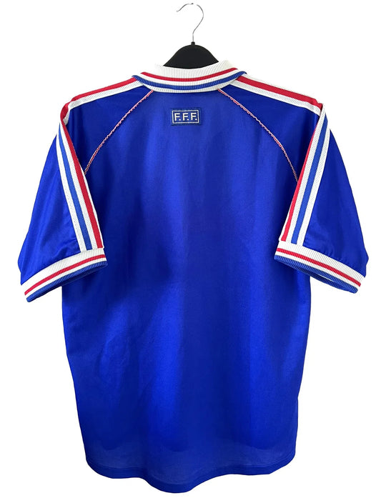 Maillot de foot vintage de l'équipe de france domicile bleu blanc et rouge. On peut retrouver l'équipementier adidas et le coq avec l'étoile. Il s'agit d'un maillot authentique