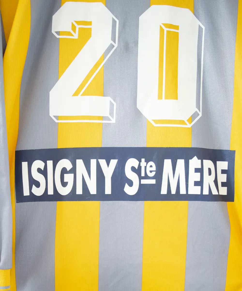 Maillot du SM Caen de la saison 2000-2001. Le maillot est de couleur gris et jaune. On peut retrouver l'équipementier le coq sportif, le sponsor infonie et le sponsor isigny sainte mère. On peut aussi retrouver l'ancien patch LNF. Le maillot est floqué du numéro 20 Faderne