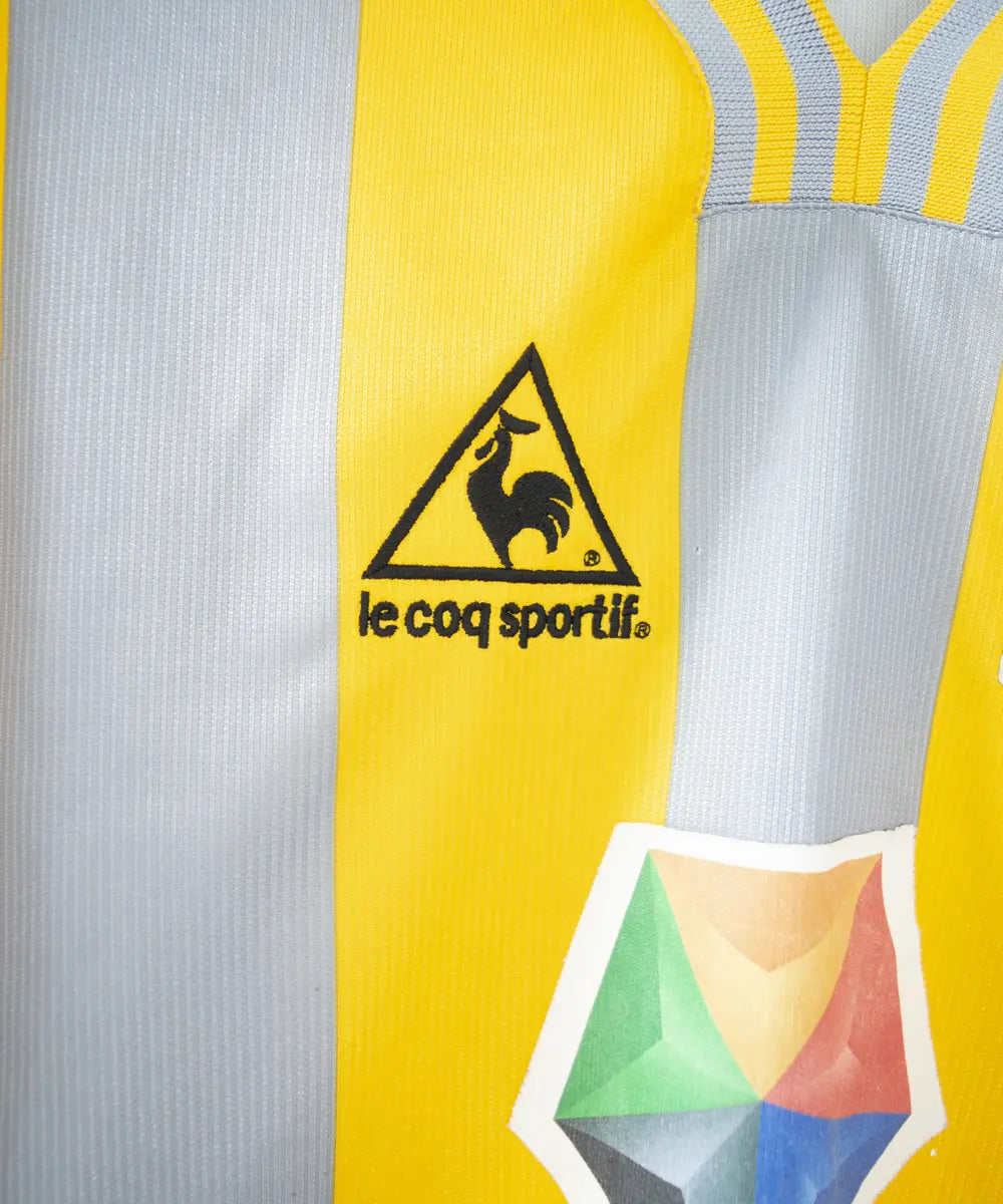 Maillot du SM Caen de la saison 2000-2001. Le maillot est de couleur gris et jaune. On peut retrouver l'équipementier le coq sportif, le sponsor infonie et le sponsor isigny sainte mère. On peut aussi retrouver l'ancien patch LNF. Le maillot est floqué du numéro 20 Faderne