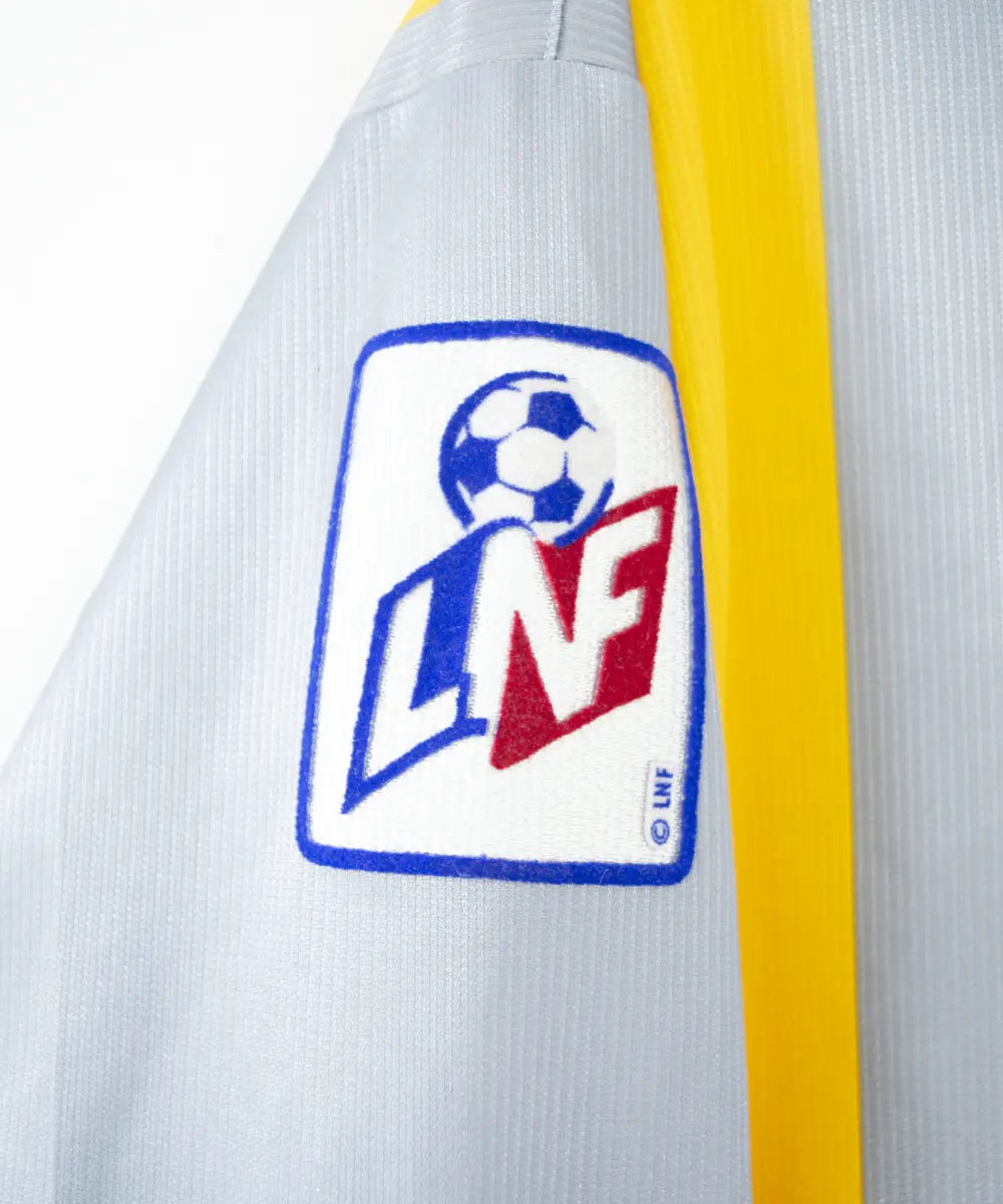Maillot du SM Caen de la saison 2000-2001. Le maillot est de couleur gris et jaune. On peut retrouver l'équipementier le coq sportif, le sponsor infonie et le sponsor isigny sainte mère. On peut aussi retrouver l'ancien patch LNF. Le maillot est floqué du numéro 20 Faderne