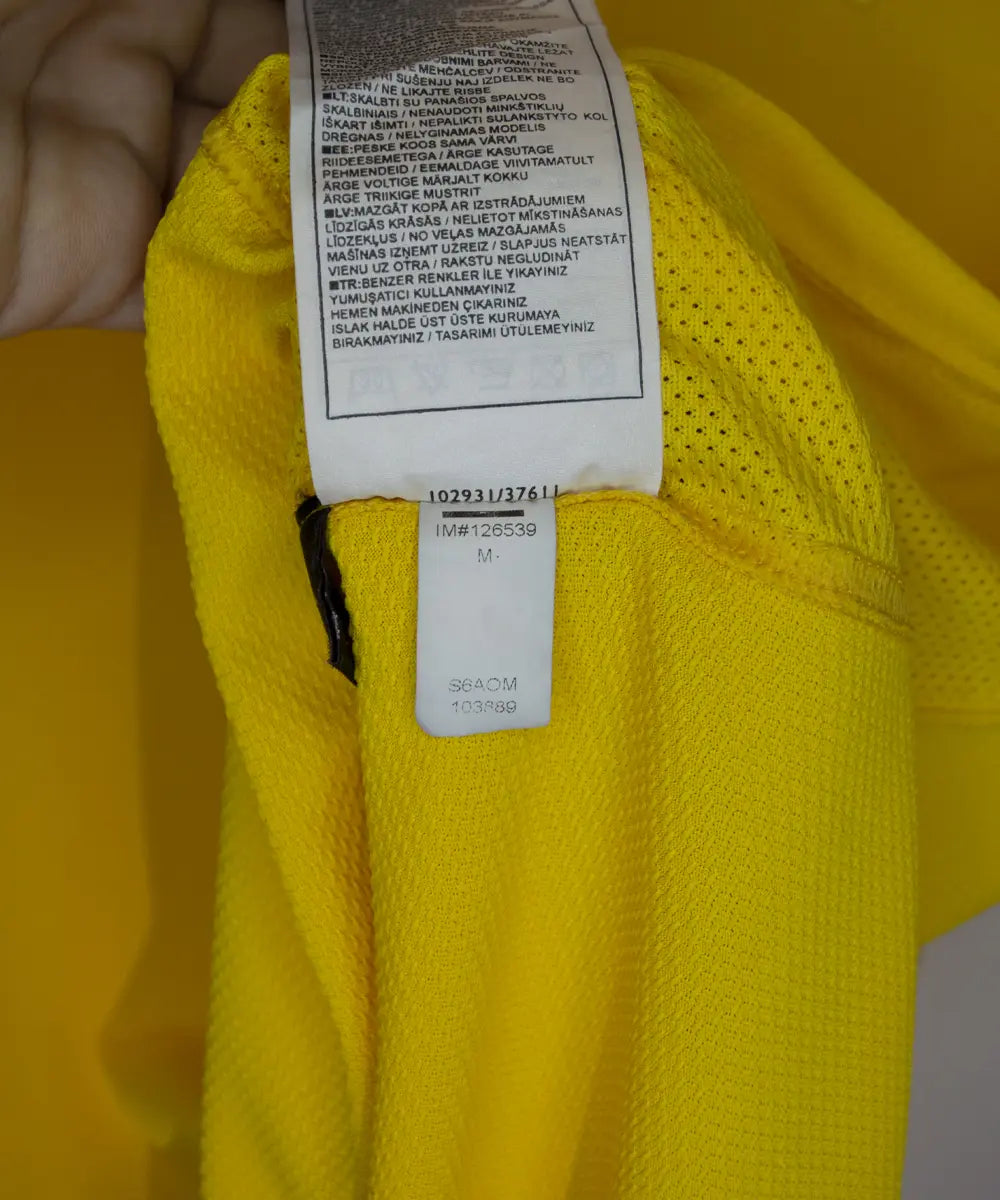 Maillot domicile jaune et vert du brésil 2006-2008. On peut retrouver l'équipementier nike. Le maillot est floqué du numéro 9 Ronaldo. Sur cette photo on peut voir l'étiquette d'authenticité comportant les numéros S6AOM