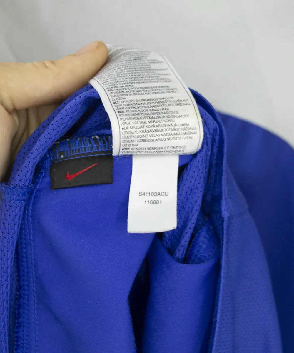 Maillot vintage bleu et blanc domicile du bresil de la saison 2004-2006. On peut retrouver l'équipementier nike. Sur cette photo on peut voir l'étiquette d'authenticité comportant les numéros S41103ACU
