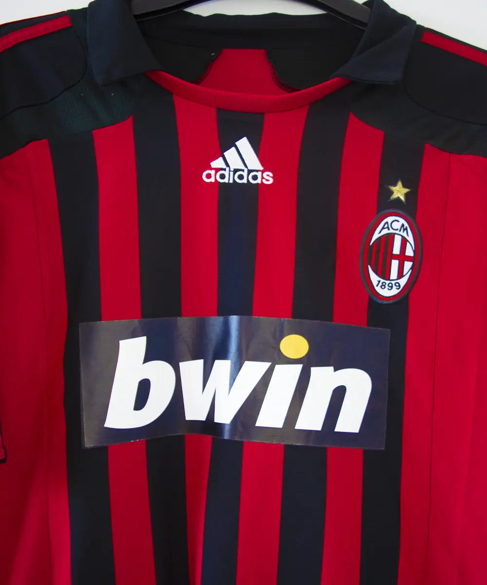 Maillot retro et vintage authentique de l'ac milan lors de la saison 2007 2008. Le maillot est de couleur rouge et noir, on peut retrouver l'équipementier adidas et le sponsor bwin. Le maillot est floqué du numéro 99 Ronaldo. Sur cette photo on peut voir le devant du maillot de près