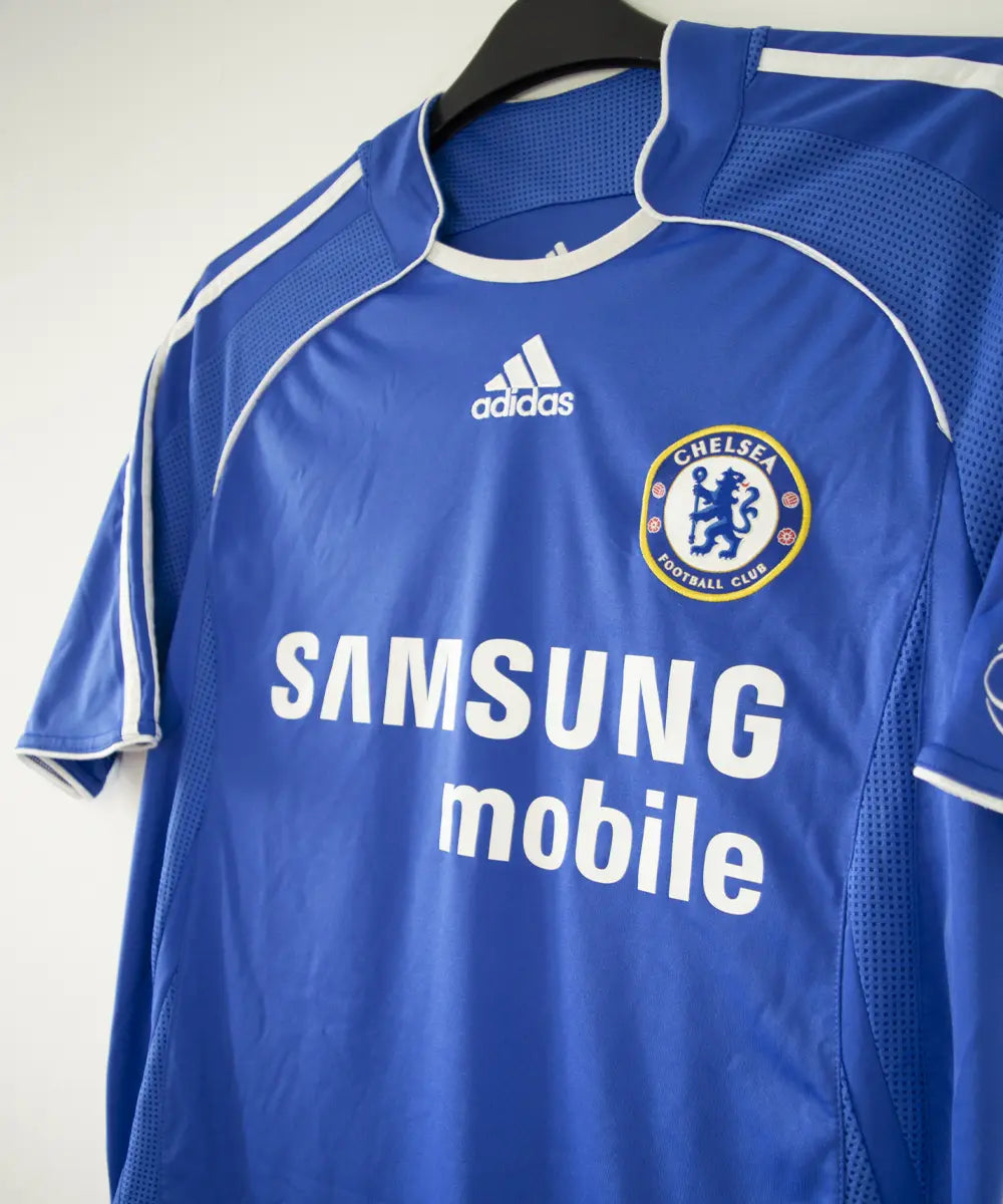 Maillot de foot vintage bleu domicile de chelsea de la saison 2006-2008. On peut retrouver l'équipementier adidas et le sponsor samsung. Le maillot est floqué du numéro 11 Didier Drogba. Le maillot possède l'étiquette 061230