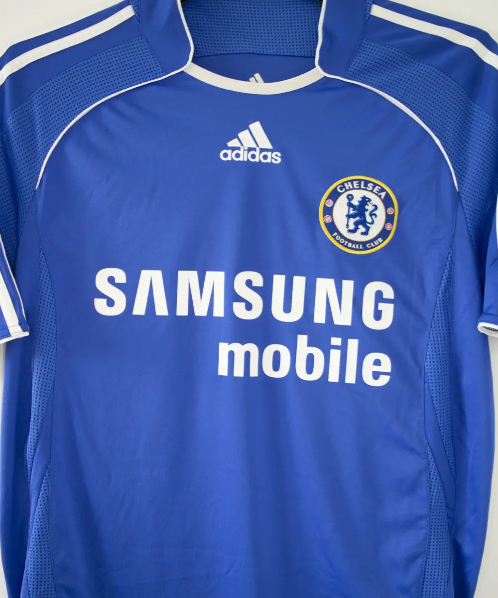 Maillot de foot vintage bleu domicile de chelsea de la saison 2006-2008. On peut retrouver l'équipementier adidas et le sponsor samsung. Le maillot est floqué du numéro 11 Didier Drogba. Le maillot possède l'étiquette 061230