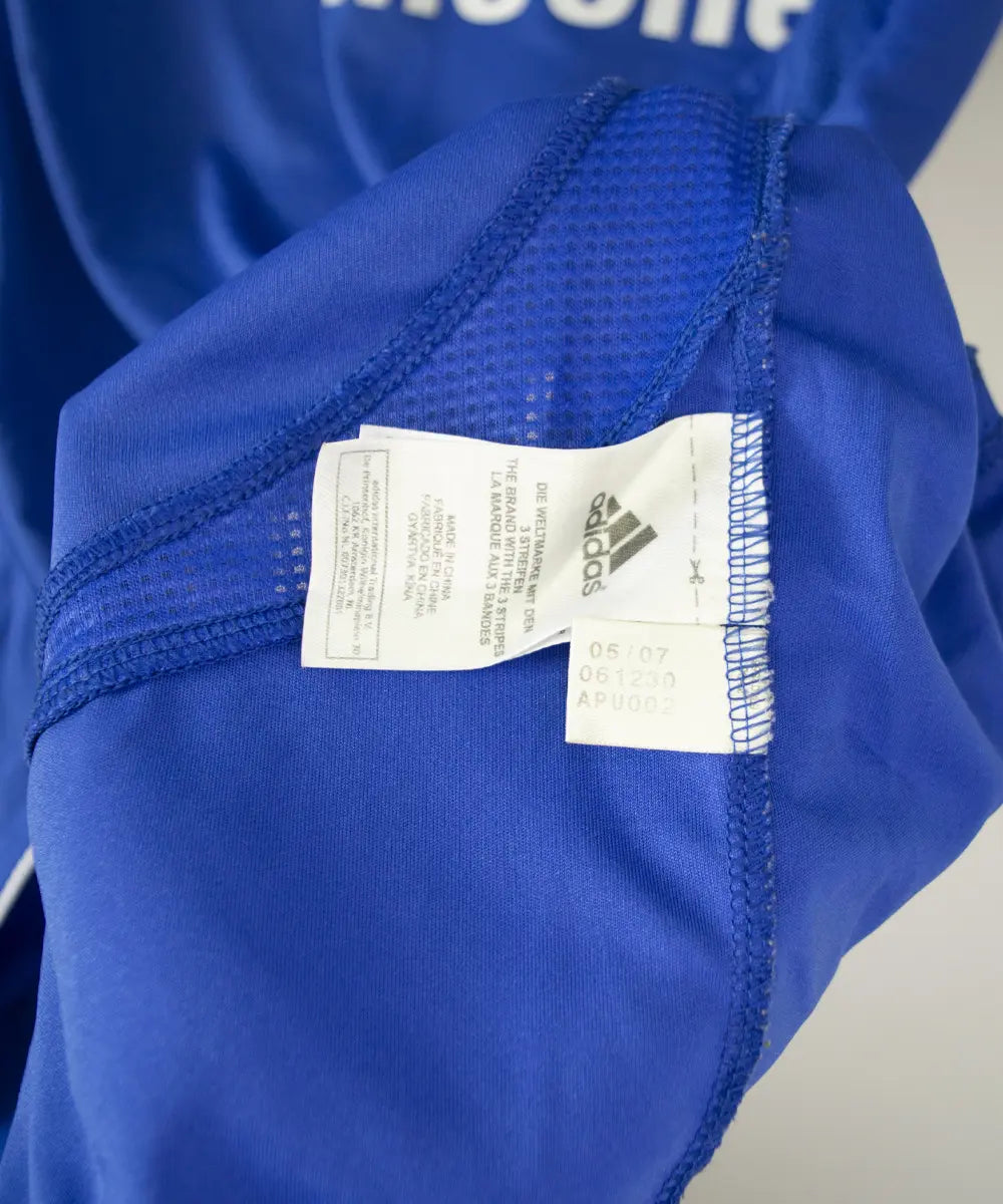 Maillot de foot vintage bleu domicile de chelsea de la saison 2006-2008. On peut retrouver l'équipementier adidas et le sponsor samsung. Le maillot est floqué du numéro 11 Didier Drogba. Le maillot possède l'étiquette 061230