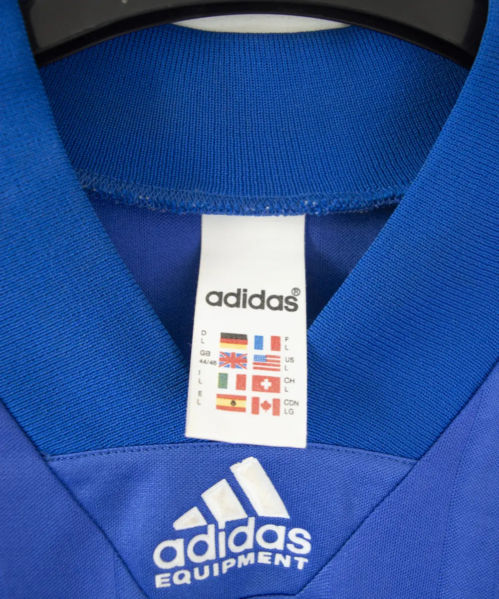 Maillot domicile de l'équipe de france 1992 de couleur bleu blanc et rouge. On peut retrouver l'équipementier adidas
