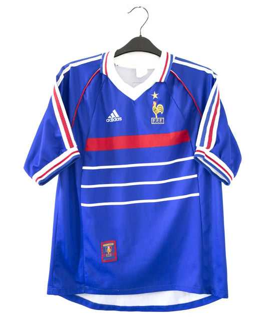 Maillot de foot authentique de l'équipe de france 1998. Le maillot est floqué du numéro 10 Zinedine Zidane. Sur cette photo on peut voir le devant du maillot avec le coq une étoile