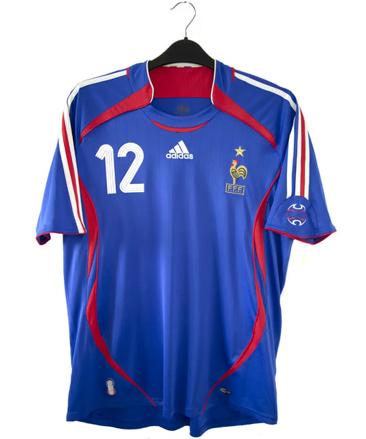 Maillot de foot vintage domicile bleu et rouge de l'équipe de france 2006. On peut retrouver l'équipementier adidas. Le maillot est floqué du numéro 12 Thierry Henry. Le maillot comporte l'étiquette 740126