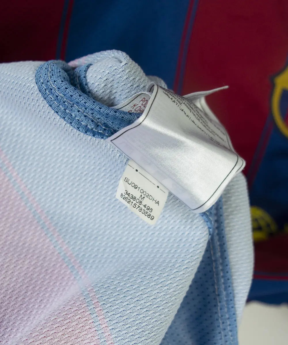 Maillot domicile du barca de la saison 2009-2010. Le maillot est de couleur bleu et rouge. On peut retrouver l'équipementier nike et le sponsor unicef. Le maillot est floqué du numéro 10 Messi. Sur cette photo on peut retrouver l'étiquette d'authenticité comportant les numéros 343808-496