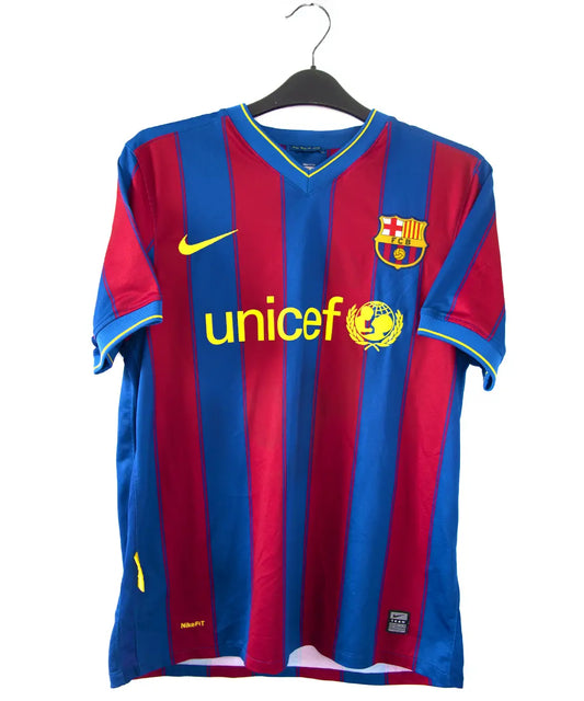 Maillot domicile du barca de la saison 2009-2010. Le maillot est de couleur bleu et rouge. On peut retrouver l'équipementier nike et le sponsor unicef. Le maillot est floqué du numéro 10 Messi
