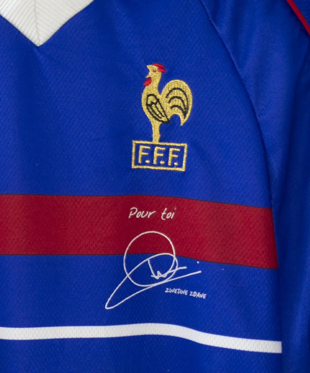 Maillot de foot vintage domicile bleu blanc et rouge de l'équipe de france 1998. On peut retrouver l'équipementier adidas. Le maillot possède la signature pour toi zinedine zidane. Il s'agit d'un maillot authentique