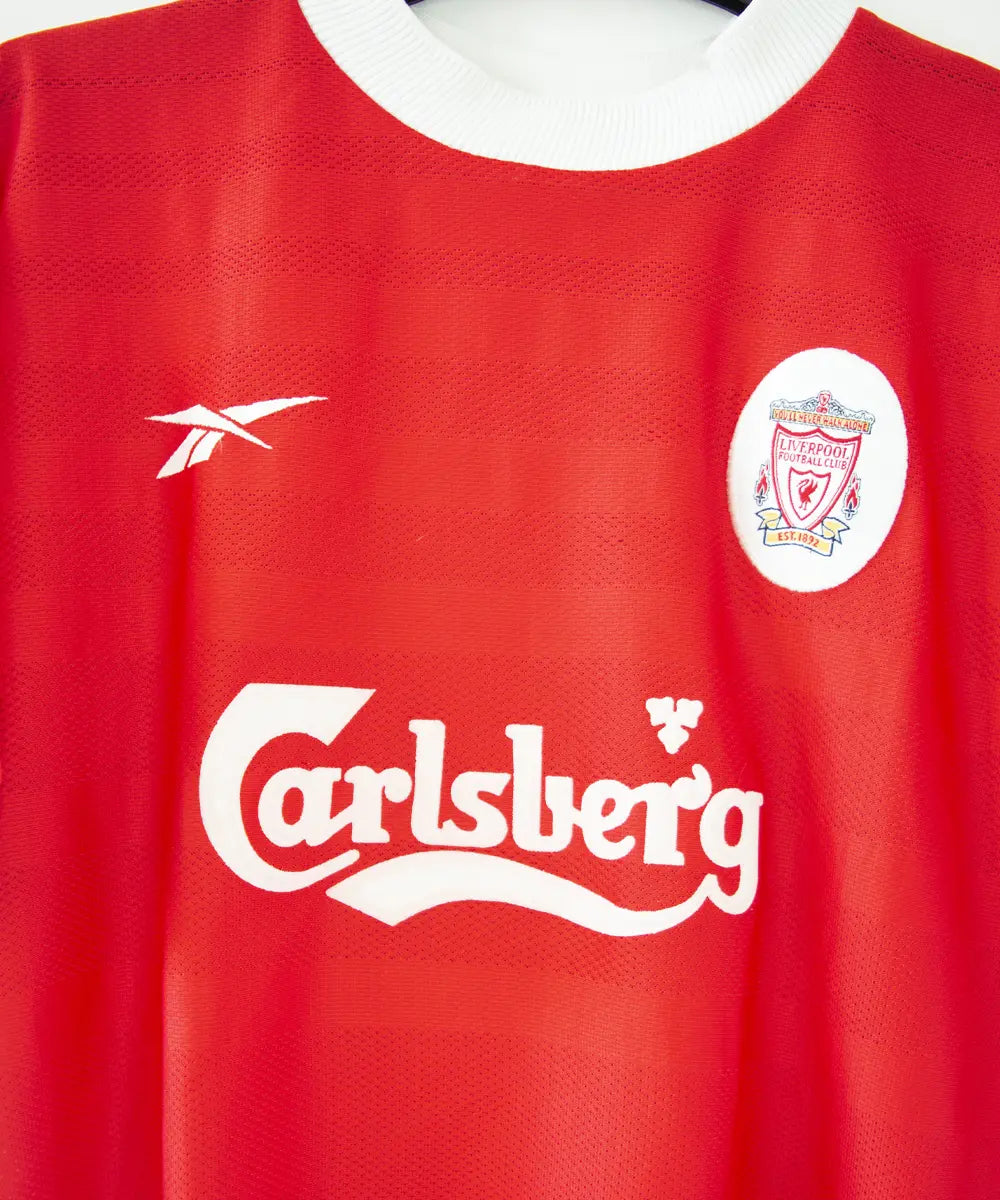 Maillot domicile de liverpool de la saison 1998-2000. Le maillot est de couleur rouge et blanc. On peut retrouver l'équipementier Reebok et le sponsor Carlsberg. Le maillot est floqué du numéro 10 Owen