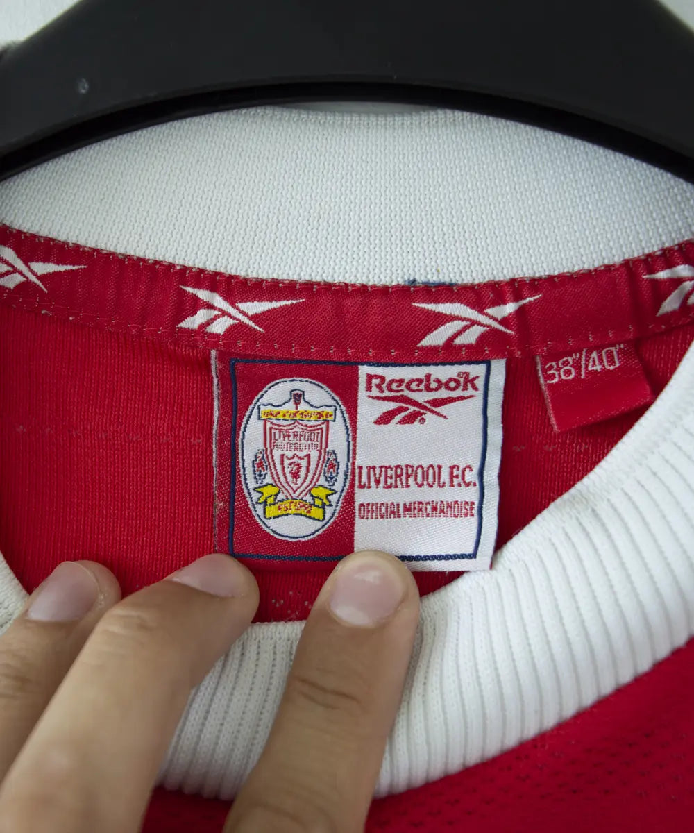 Maillot domicile de liverpool de la saison 1998-2000. Le maillot est de couleur rouge et blanc. On peut retrouver l'équipementier Reebok et le sponsor Carlsberg. Le maillot est floqué du numéro 10 Owen. Sur cette photo on peut voir l'étiquette Reebok