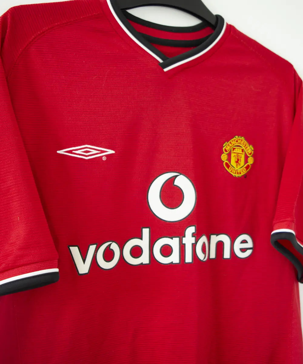 Maillot domicile rouge et noir de manchester united édité lors de la saison 2000-2002. On peut retrouver l'équipementier umbro et le sponsor vodafone
