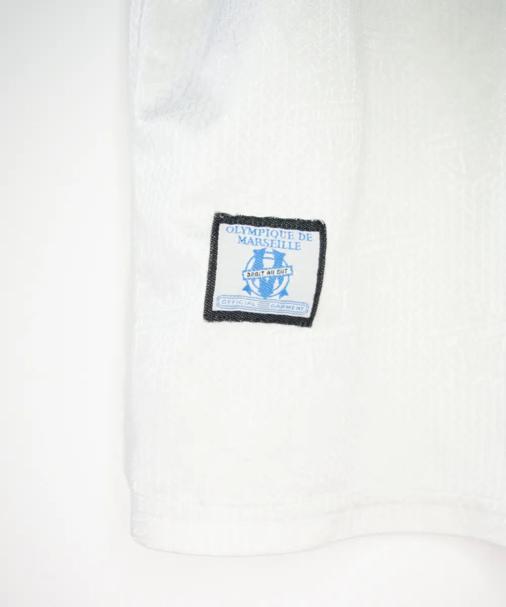 Maillot vintage domicile banc et bleu de l'OM de la saison 1997-1998. On peut retrouver l'équipementier adidas et le sponsor ericsson