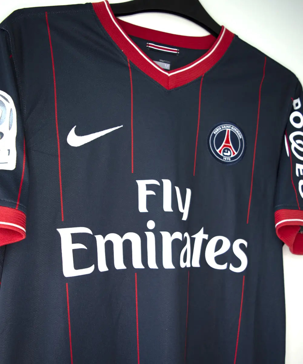 Maillot domicile du psg de la saison 2009 2010. Le maillot est de couleur bleu avec des rayures rouges. On peut retrouver l'équipementier nike, le sponsor fly emirates et le sponsor poweo. Le maillot est floqué ludovic Giuly. Sur cette photo on peut voir le devant du maillot de côté