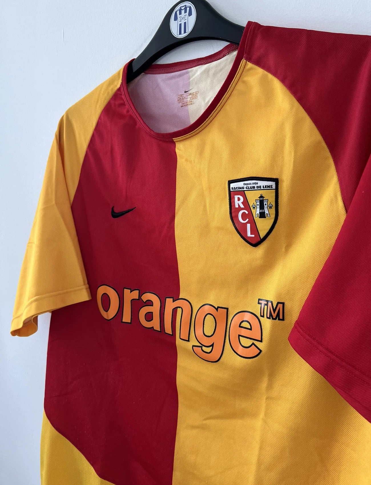 Maillot de foot vintage domicile du rc lens de la saison 2003-2004. On peut retrouver l'équipementier nike et le sponsor Orange. Le maillot est de couleur jaune et rouge. Il s'agit d'un maillot authentique comportant l'étiquette avec les numéros 112760
