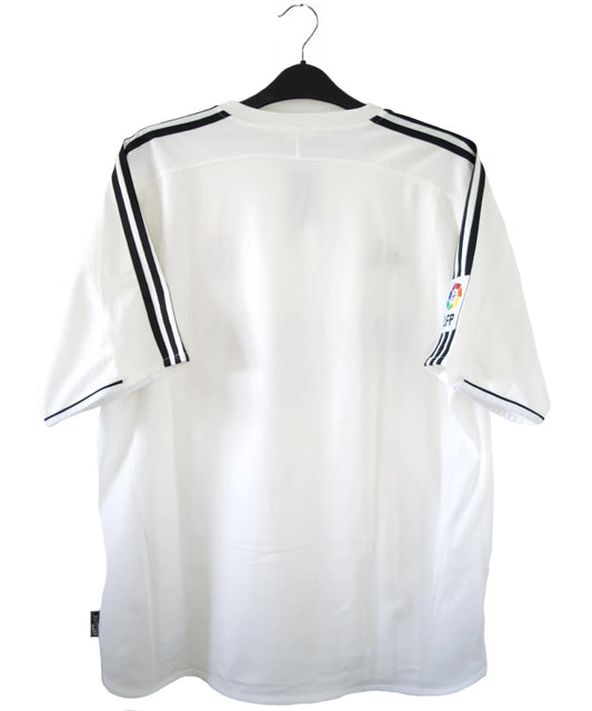 Maillot de foot vintage domicile blanc et noir du real madrid de la saison 2003/2004. On peut retrouver l'équipementier adidas et le sponsor siemens mobile. On peut retrouver l'étiquette d'authenticité du maillot comportant les numéros 021804