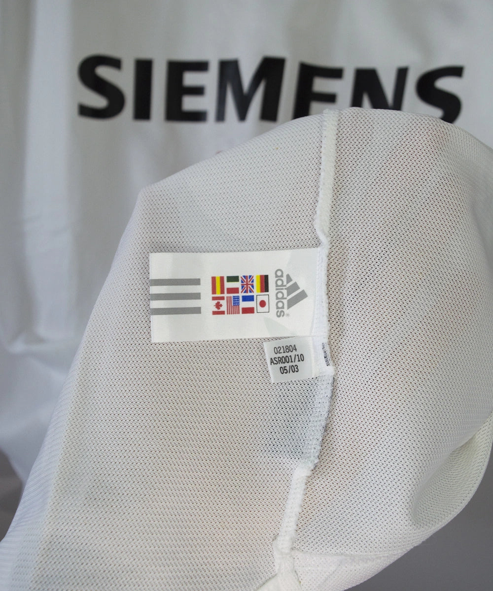 Maillot de foot vintage domicile blanc et noir du real madrid de la saison 2003/2004. On peut retrouver l'équipementier adidas et le sponsor siemens mobile. On peut retrouver l'étiquette d'authenticité du maillot comportant les numéros 021804