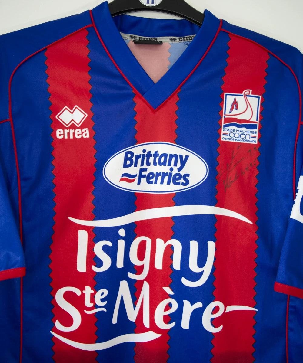 Maillot de foot vintage domicile du Stade Malherbe Caen édité lors de la finale de la Coupe de la Ligue lors de la saison 2004-2005. On peut retrouver l'équipementier Errea, le sponsor isigny Ste Mère, Brittany Ferries, Phillips et GDE. Le maillot est signé par Ibrahima Faye. Il s'agit d'un maillot authentique