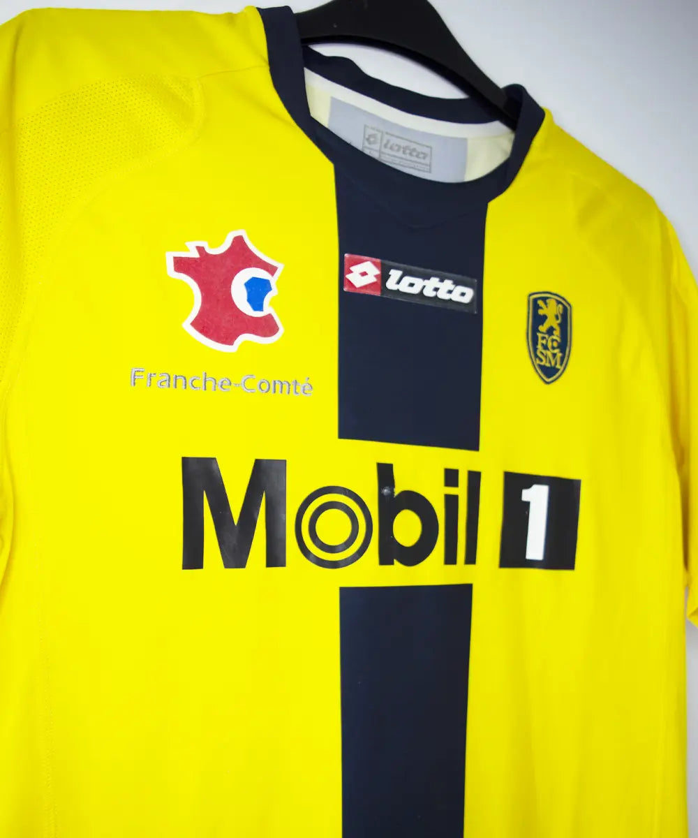 Maillot domicile du Sochaux Montbéliard FC de couleur jaune et bleu de la saison 2008-2009. On peut retrouver l'équipementier Lotto et le sponsor Mobile 1. Le maillot est floqué du numéro 9 Mevlut Erding