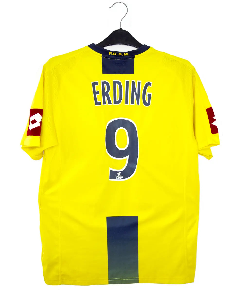 Maillot domicile du Sochaux Montbéliard FC de couleur jaune et bleu de la saison 2008-2009. On peut retrouver l'équipementier Lotto et le sponsor Mobile 1. Le maillot est floqué du numéro 9 Mevlut Erding