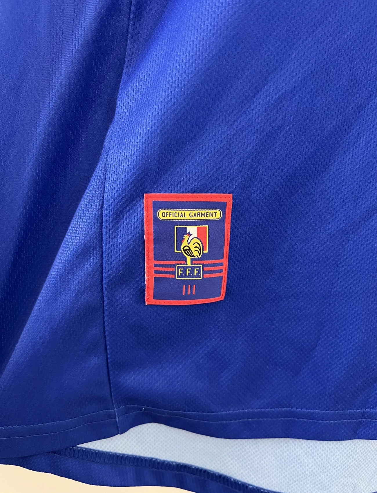 Maillot de foot vintage bleu, blanc et rouge de l'équipe de france 1998. On peut retrouver l'équipementier adidas. Il s'agit d'un maillot authentique d'époque