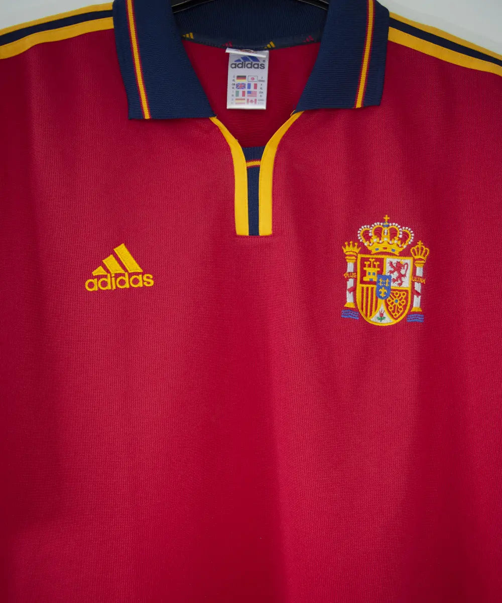 Maillot domicile de l'espagne de couleur rouge, bleu et jaune de 1999 à 2002. On peut retrouver l'équipementier adidas.