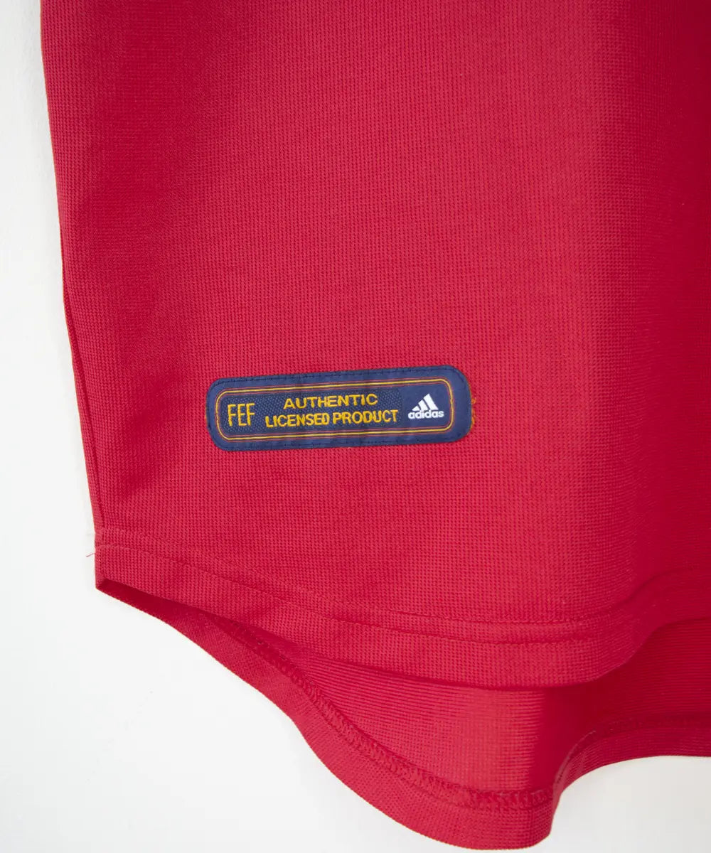 Maillot domicile de l'espagne de couleur rouge, bleu et jaune de 1999 à 2002. On peut retrouver l'équipementier adidas.