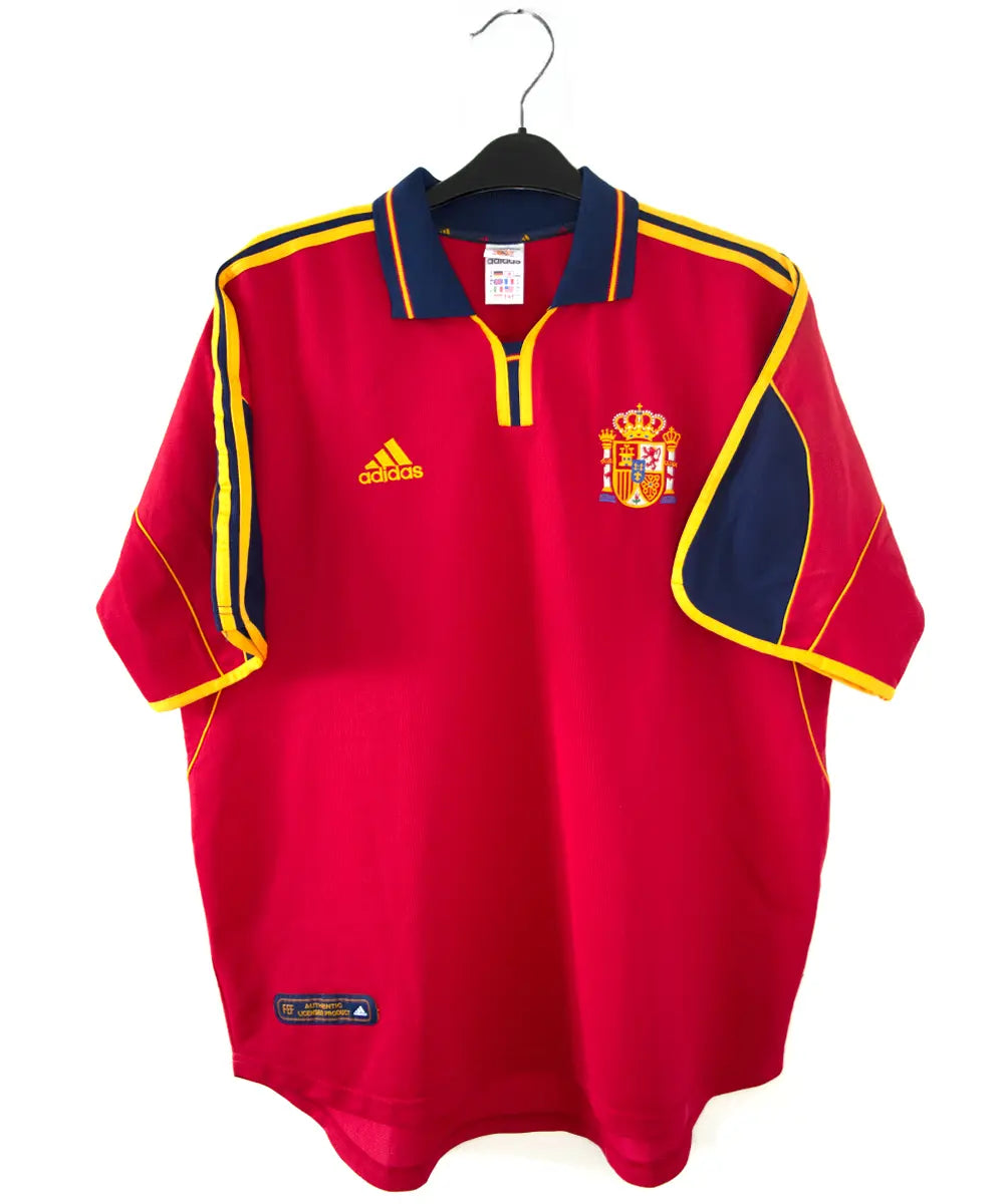 Maillot domicile de l'espagne de couleur rouge, bleu et jaune de 1999 à 2002. On peut retrouver l'équipementier adidas.