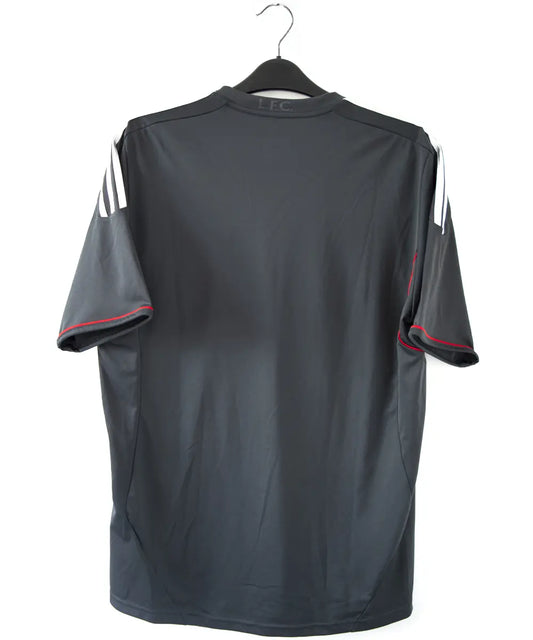 Maillot extérieur de liverpool de la saison 2011-2012. Le maillot est de couleur noir, gris et rouge. On peut retrouver l'équipementier adidas et le sponsor standard chartered.