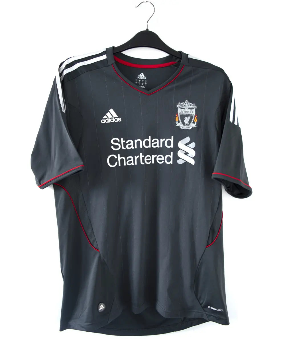 Maillot extérieur de liverpool de la saison 2011-2012. Le maillot est de couleur noir, gris et rouge. On peut retrouver l'équipementier adidas et le sponsor standard chartered.