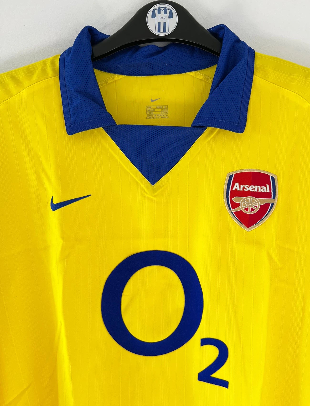 Maillot de foot vintage extérieur jaune d'arsenal de la saison 2003/2004. On peut retrouver l'équipementier Nike et le sponsor O2. Il s'agit d'un maillot authentique d'époque.