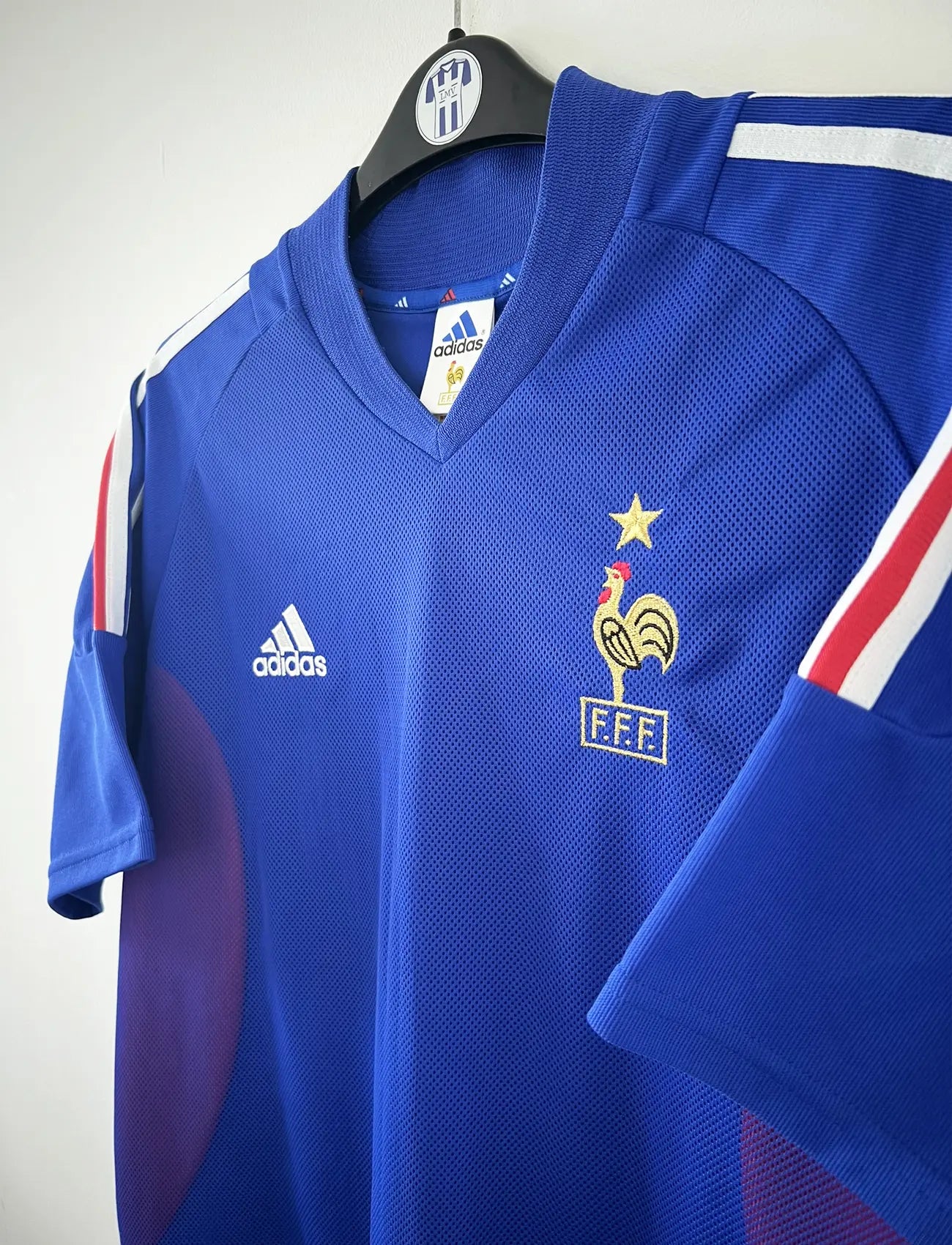 Maillot de foot vintage domicile de l'équipe de france 2002. Le maillot est de couleur bleu blanc et rouge. On peut retrouver l'équipementier adidas. Le maillot est floqué du numéro 10 Zinedine Zidane. Il s'agit d'un maillot authentique d'époque comportant les numéros 139531.