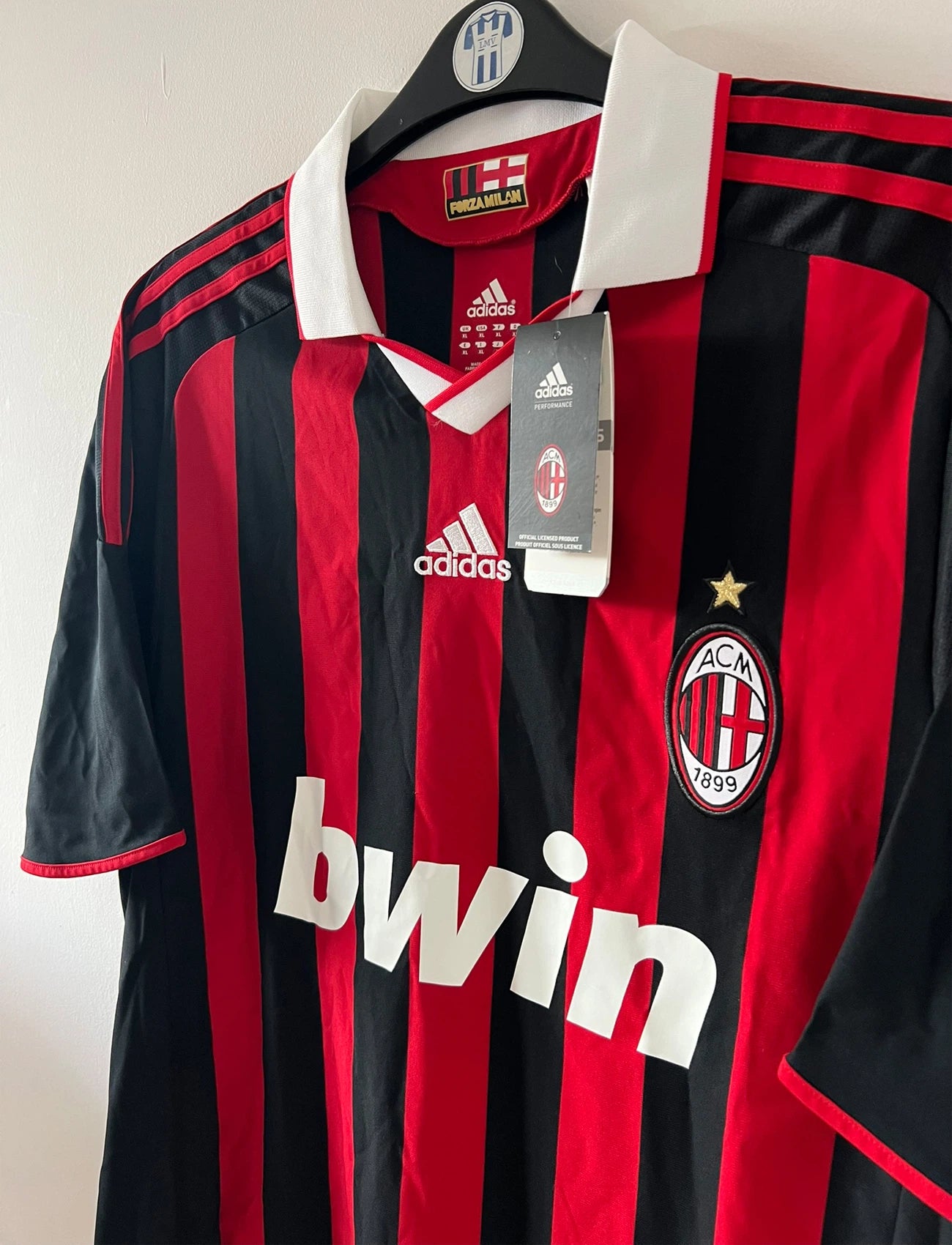 Maillot de foot vintage domicile rouge et noir de l'AC Milan saison 2009/2010. On peut retrouver l'équipementier Adidas et le sponsor Bwin. Il s'agit d'un maillot authentique d'époque.