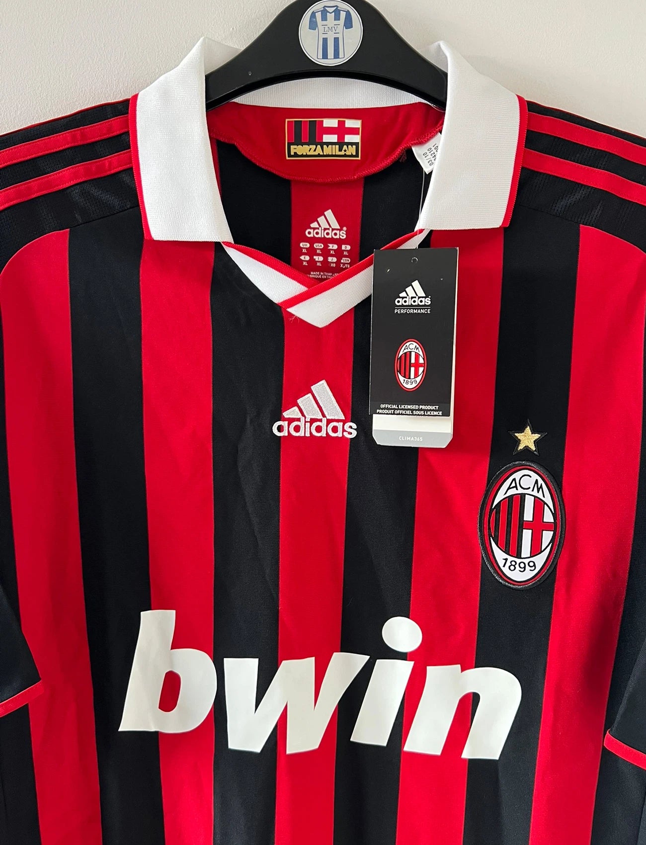 Maillot de foot vintage domicile rouge et noir de l'AC Milan saison 2009/2010. On peut retrouver l'équipementier Adidas et le sponsor Bwin. Il s'agit d'un maillot authentique d'époque.