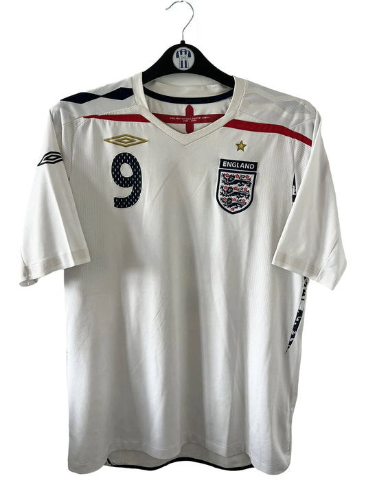 Maillot de foot vintage domicile blanc de l'Angleterre de la saison 2008-2009. On peut y retrouver l'équipementier Umbro. Le maillot est floqué du numéro 9 Rooney. Il s'agit d'un maillot authentique d'époque
