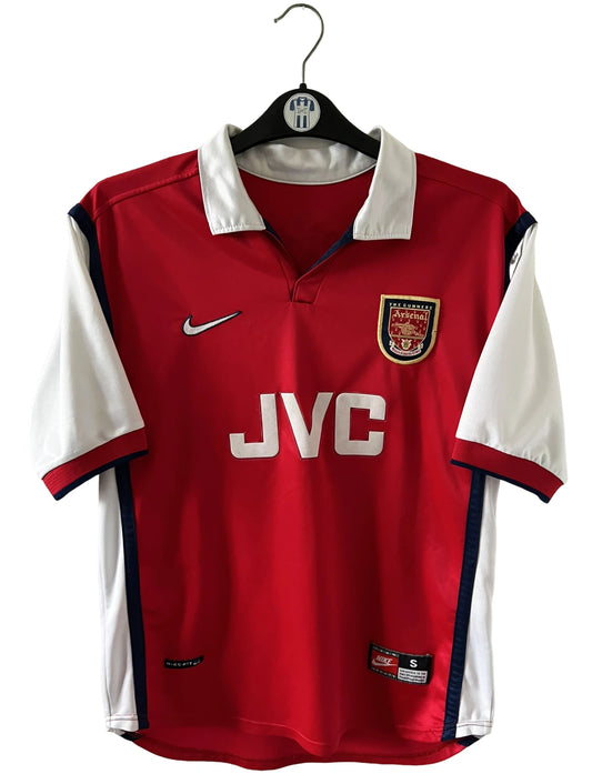 Maillot de foot vintage domicile rouge et blanc d'arsenal de la saison 1998/1999. On peut retrouver l'équipementier Nike et le sponsor JVC. Le maillot est floqué du numéro 10 Dennis Bergkamp. Il s'agit d'un maillot authentique d'époque.