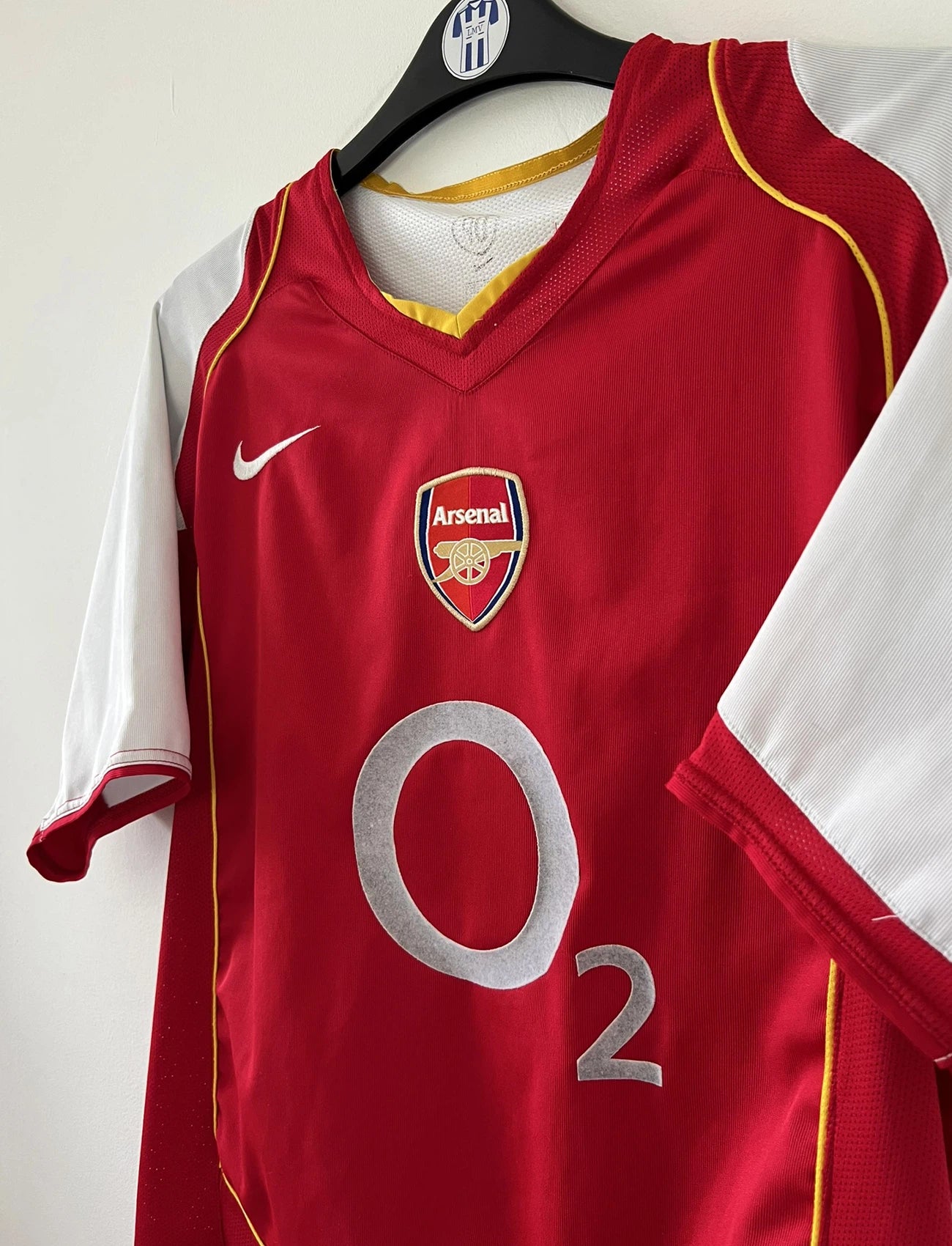 Maillot de foot vintage domicile d'arsenal de la saison 2004/2005. Le maillot est de couleur rouge et blanc. On peut retrouver l'équipementier nike et le sponsor O2 en feutrine. Il s'agit d'un maillot authentique d'époque.