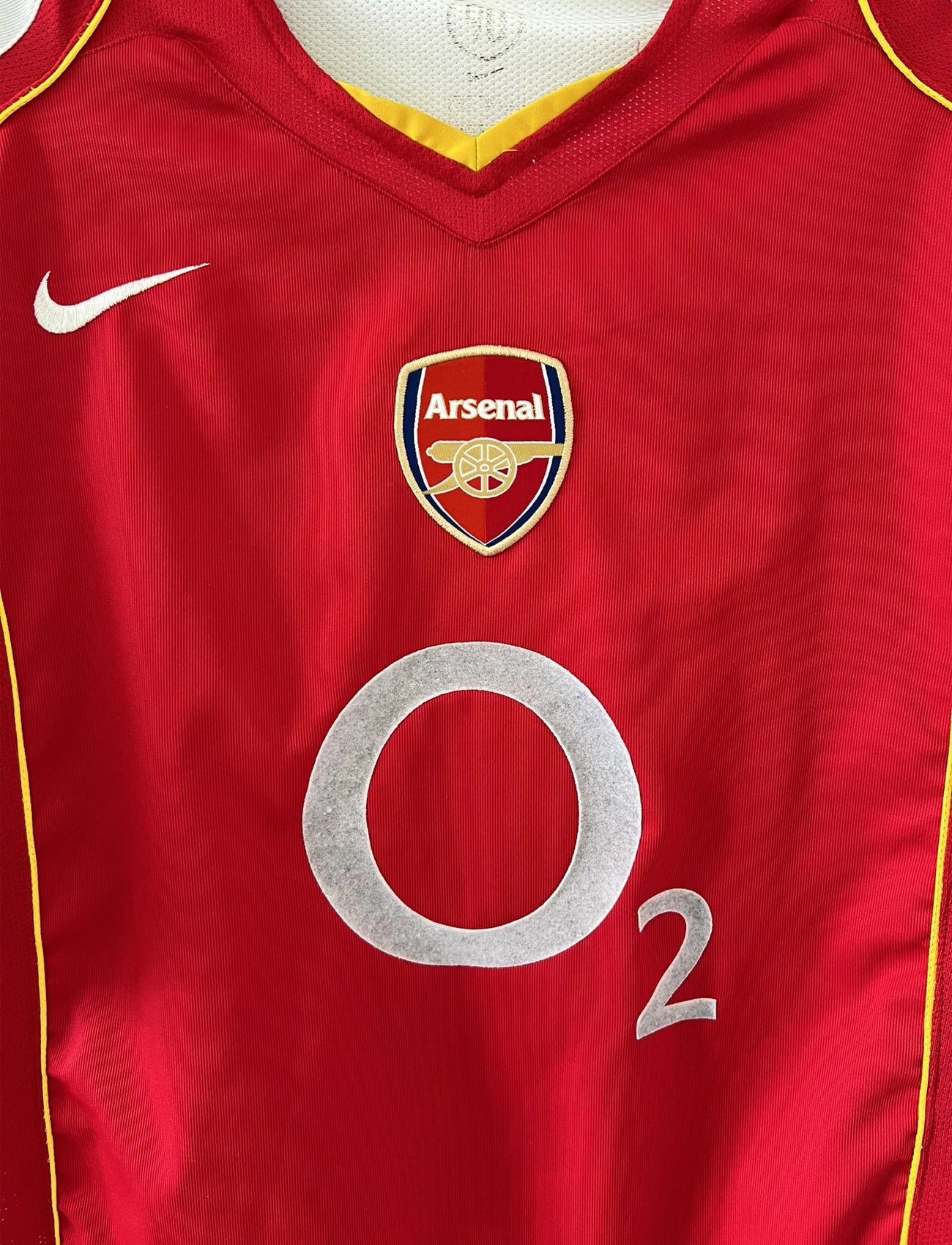 Maillot de foot vintage domicile d'arsenal de la saison 2004/2005. Le maillot est de couleur rouge et blanc. On peut retrouver l'équipementier nike et le sponsor O2 en feutrine. Il s'agit d'un maillot authentique d'époque.
