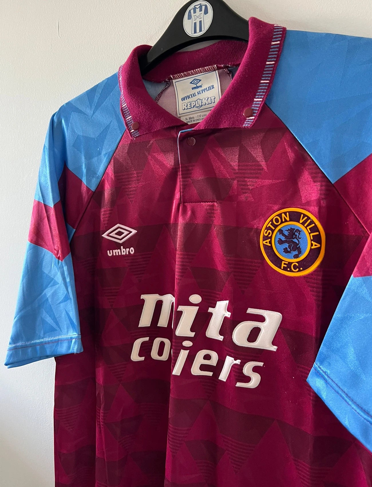 Maillot de foot vintage domicile rouge et bleu d'aston villa de la saison 1990/1992. On peut retrouver l'équipementier Umbro et le sponsor Mita Copiers. Il s'agit d'un maillot authentique d'époque.