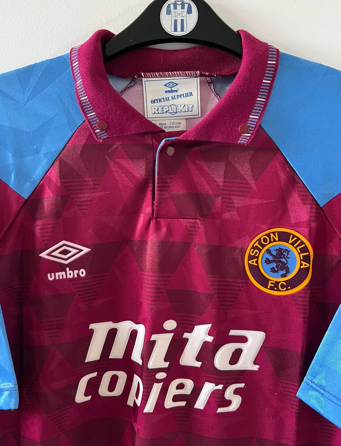 Maillot de foot vintage domicile rouge et bleu d'aston villa de la saison 1990/1992. On peut retrouver l'équipementier Umbro et le sponsor Mita Copiers. Il s'agit d'un maillot authentique d'époque.