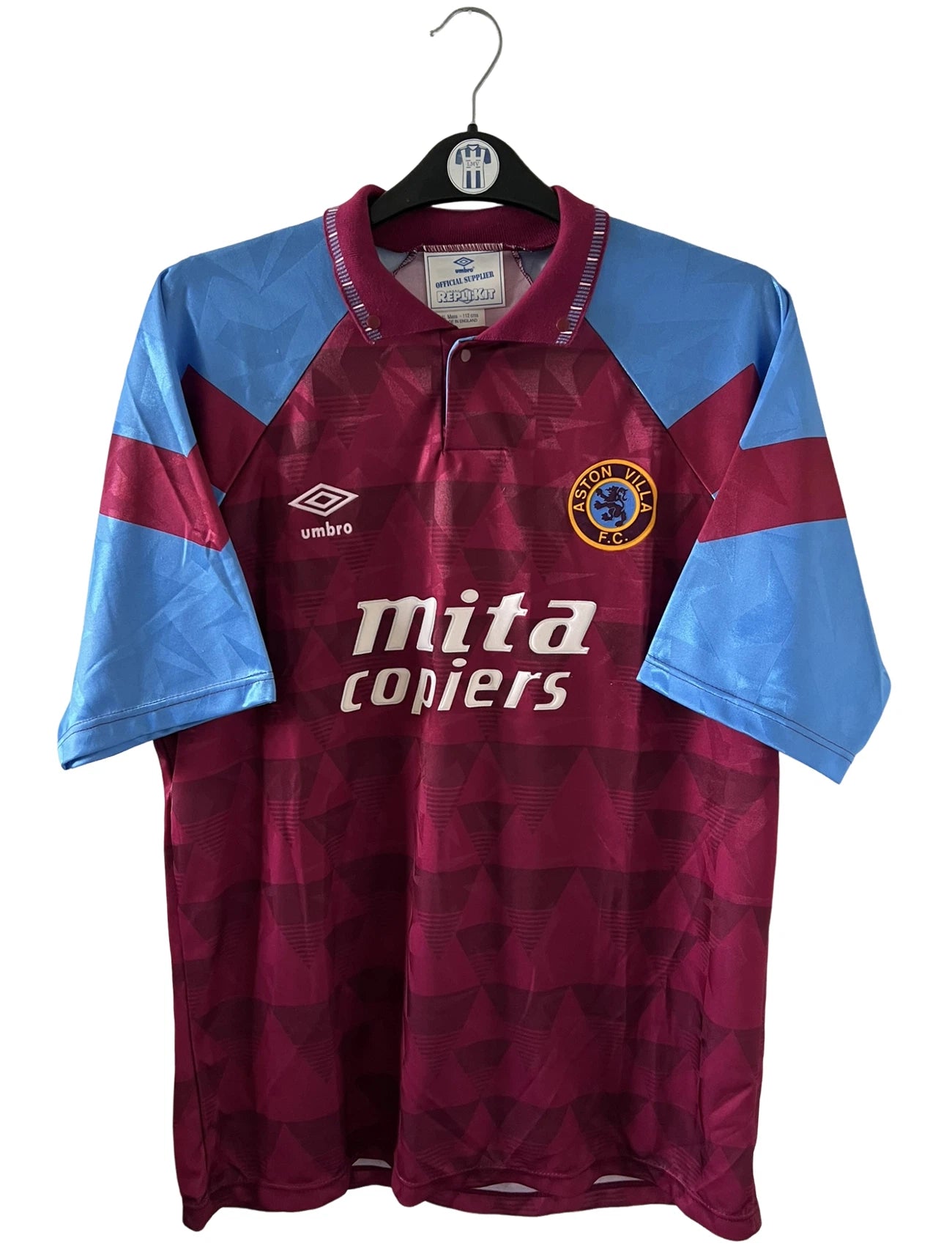 Maillot de foot vintage domicile rouge et bleu d'aston villa de la saison 1990/1992. On peut retrouver l'équipementier Umbro et le sponsor Mita Copiers. Il s'agit d'un maillot authentique d'époque.