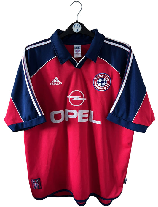 Maillot de foot vintage domicile rouge du Bayern Munich 1999/2001. On peut retrouver l'équipementier Adidas et le sponsor Opel. Le maillot est floqué du numero 3 Bixente Lizarazu. Il s'agit d'un maillot authentique d'époque.