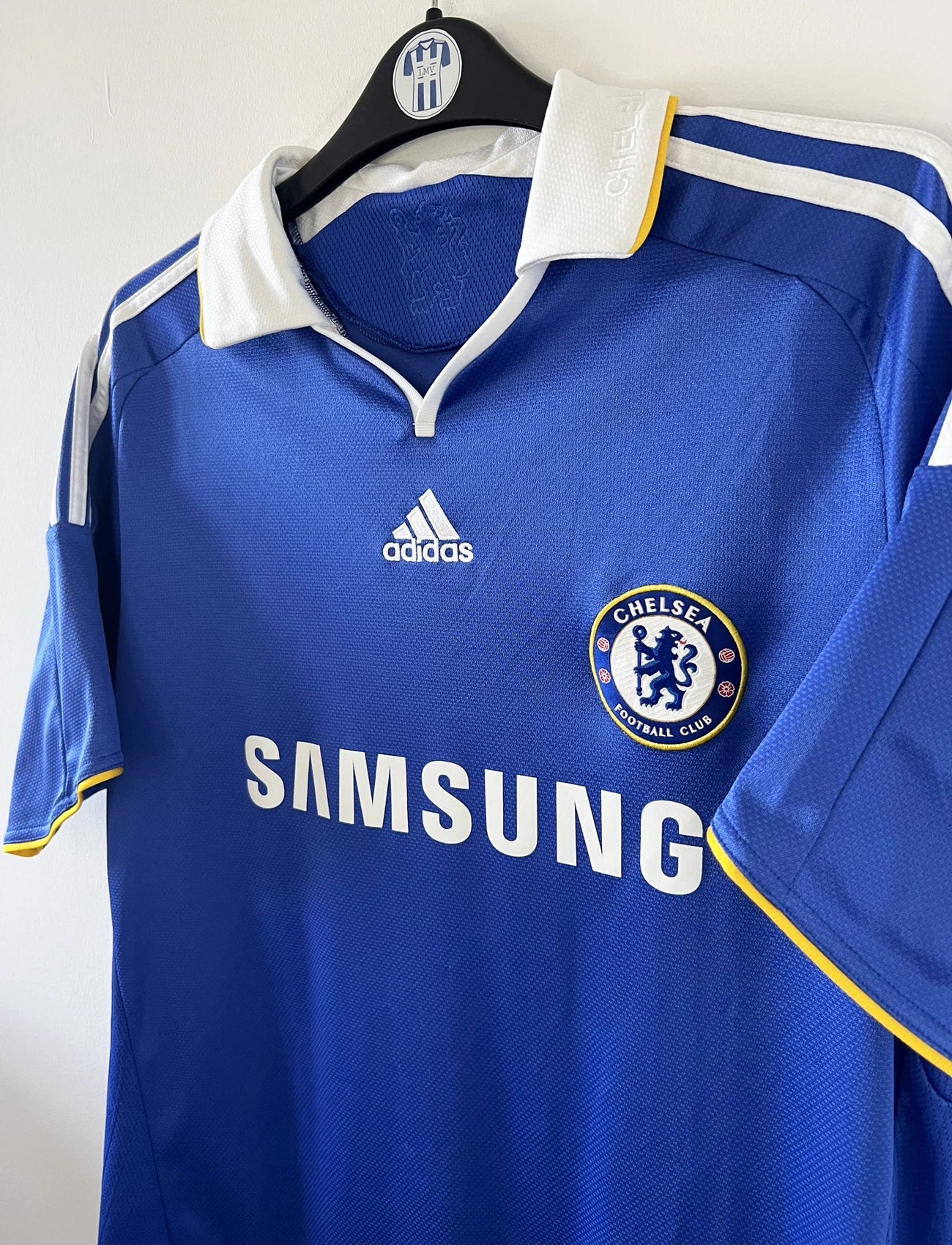 Maillot de foot vintage domicile bleu de chelsea de la saison 2008/2009. On peut retrouver l'équipementier adidas et le sponsor Samsung. Le maillot est floqué du numéro 11 Didier Drogba. Il s'agit d'un maillot authentique d'époque comportant le numéro 656133