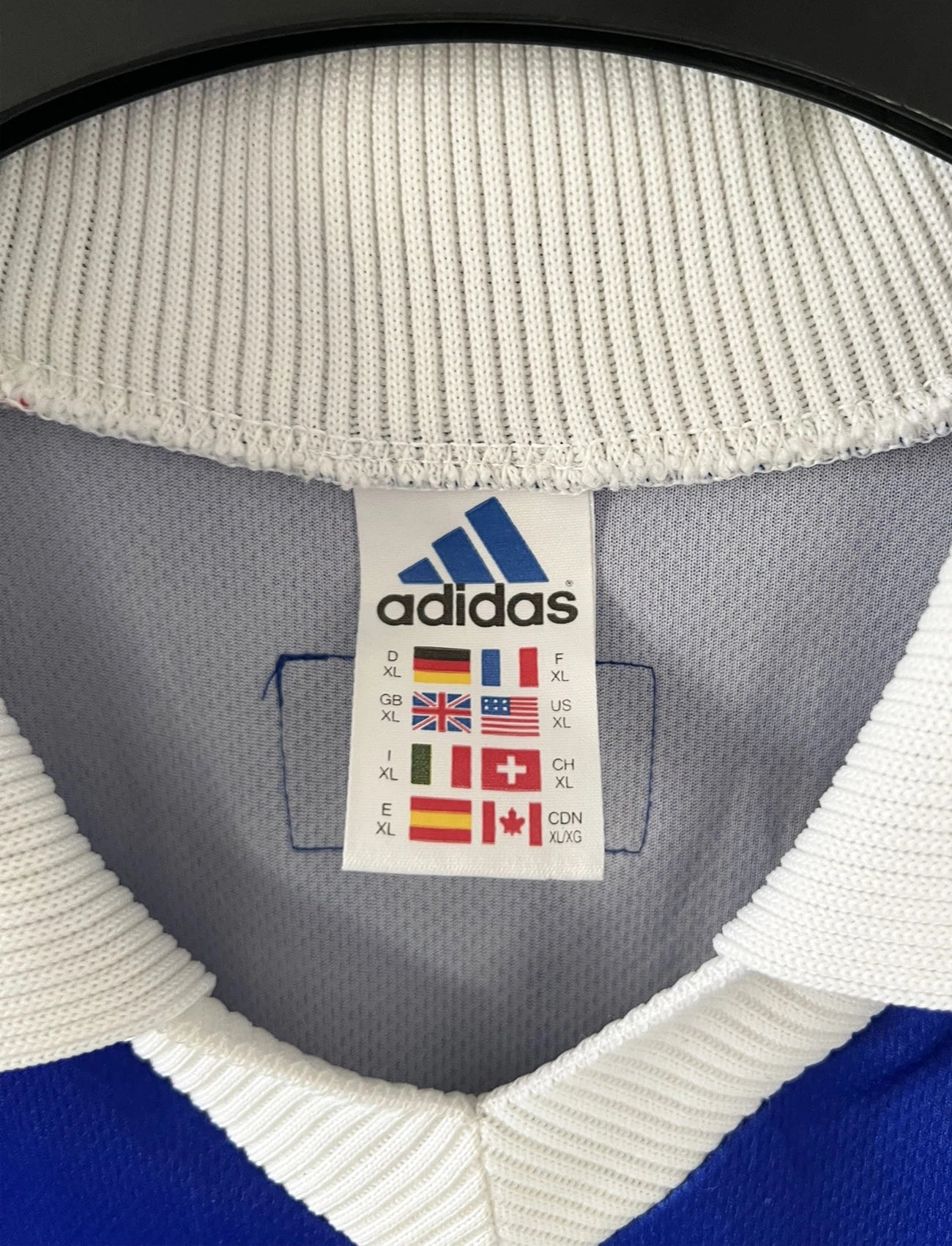 Maillot de foot vintage bleu, blanc et rouge de l'équipe de france 1998. On peut retrouver l'équipementier adidas. Il s'agit d'un maillot authentique édité avant la finale de la coupe du monde car celui-ci ne possède pas l'étoile. Le maillot possède la mention pour toi avec la signature de zidane