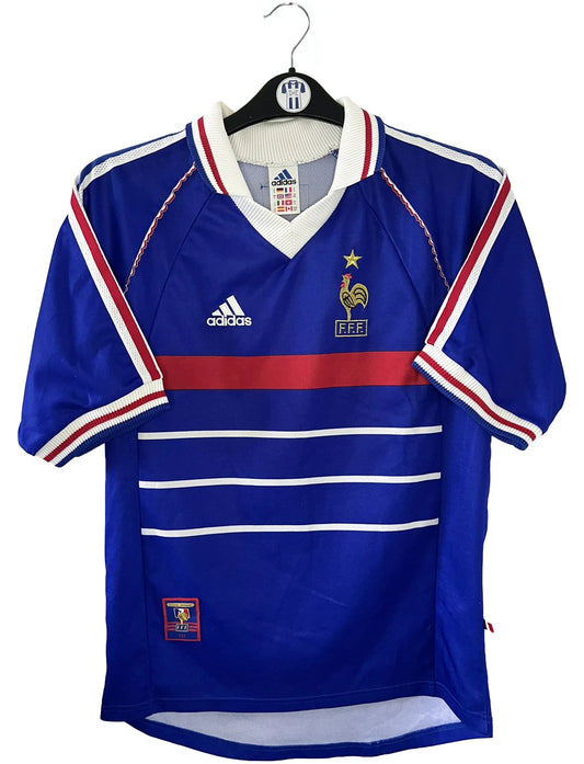 Maillot de foot vintage domicile bleu de l'équipe de france 1998. On peut retrouver l'équipementier Adidas. Le maillot est floqué du numéro 10 Zinedine Zidane. Il s'agit d'un maillot authentique d'époque.
